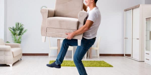 man lifting a single chair in a living room