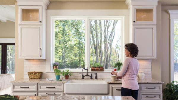 a black woman stirring coffee in the kitchen while staring out the window