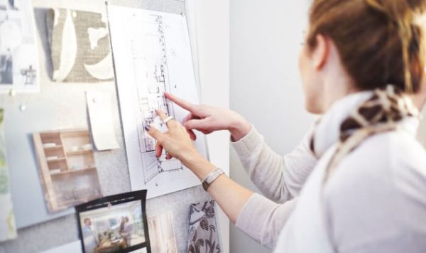 a woman pointing at a blue print on the wall