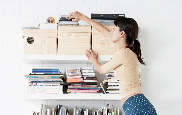 a woman trying to get something from a box on the shelf