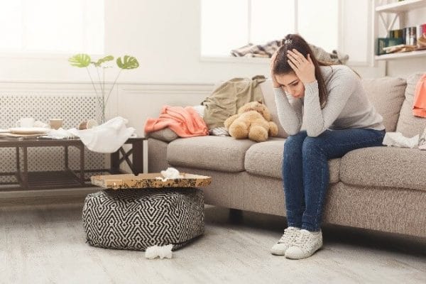 a worried woman trying to figure out how to clean her clutter in the living room