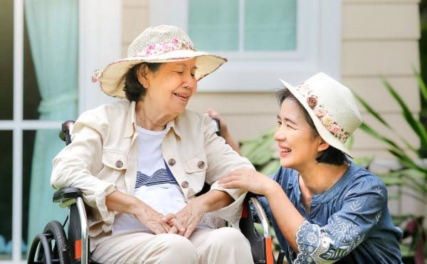 an elderly woman sitting on a wheelchair while her daughter sits beside her