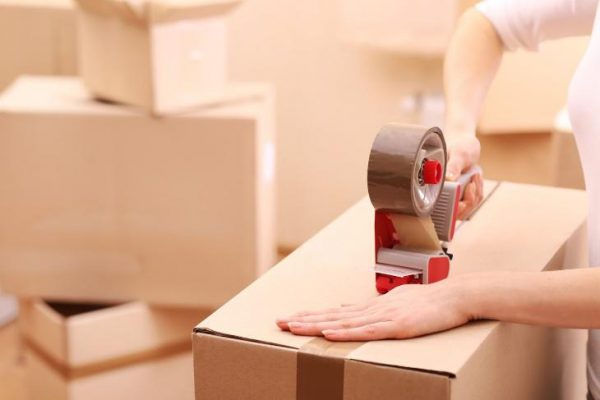 a woman sealing a box with tape