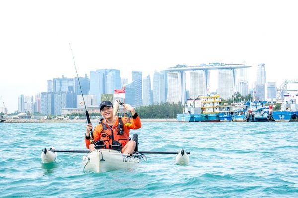 a man holding a fish he caught while kayaking