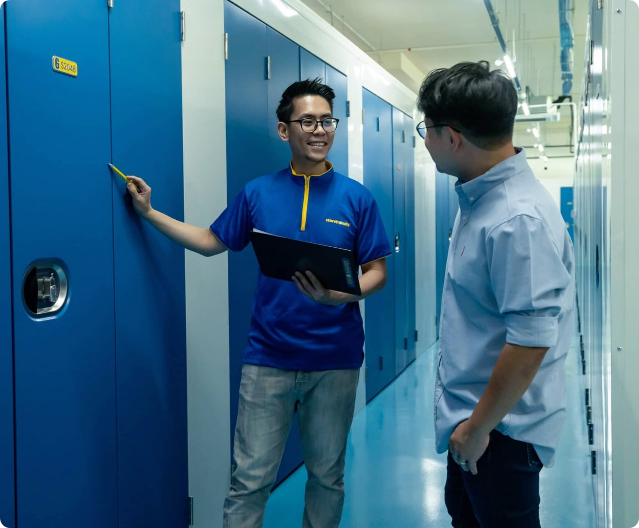 Rectangle 78@2x Two men talking to each other in a storage facility