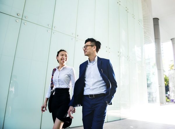 a businessman and a businesswoman walking alongside together