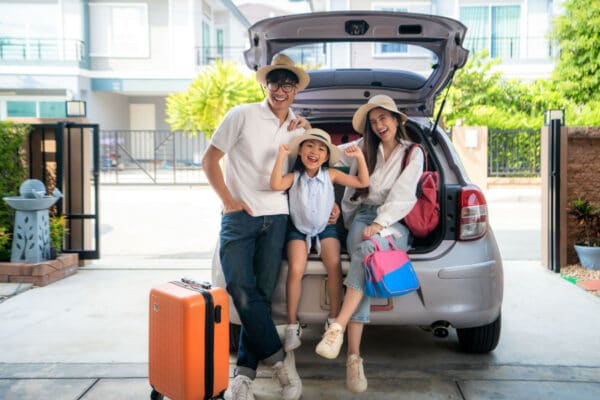 A young Asian family all packed up and ready to travel by car