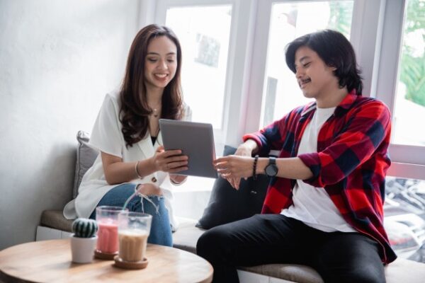 a woman showing something off to her boyfriend from her tablet