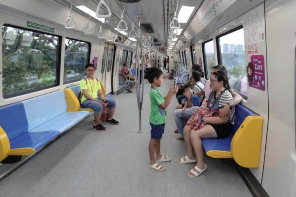 A boy taking a picture of his mom and dad in the MRT