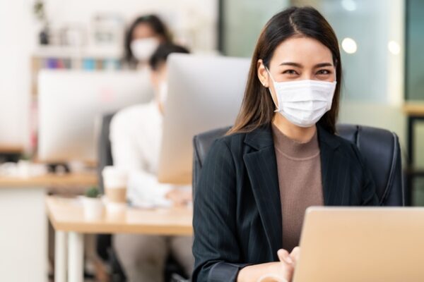 A woman wearing a face mask while working in an office