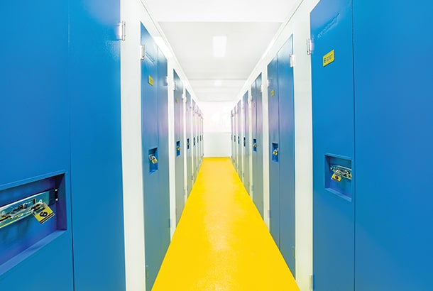 Storage units with blue doors and a yellow floor hallway