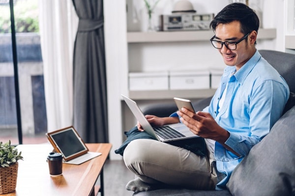 A business man sitting on his couch and using his mobile phone