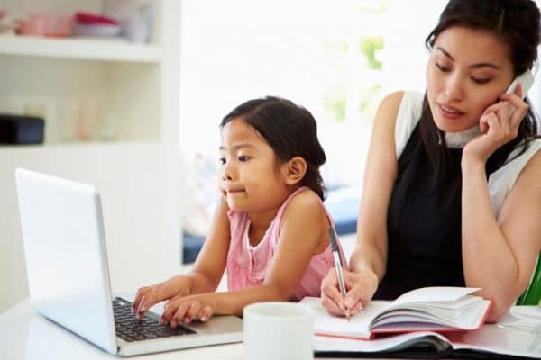 a work from home mother letting her daughter use the laptop